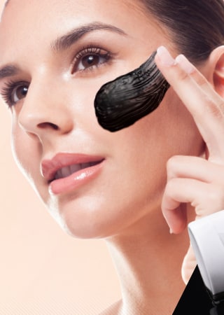 A woman smoothing a black peel-off face masque onto her cheek