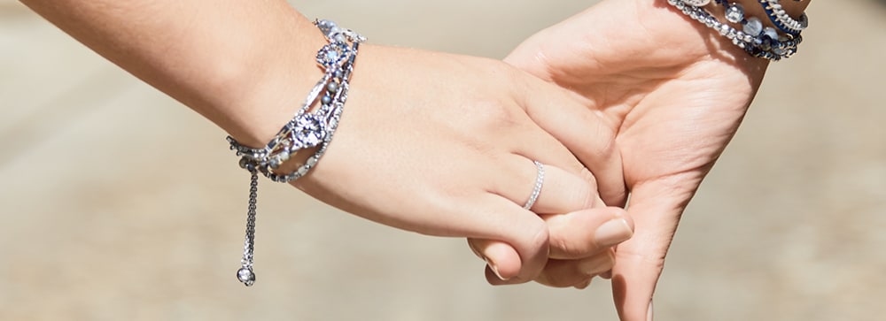 Two women holding hands, both wearing stacked Chloe + Isabel bracelets in silver and blue