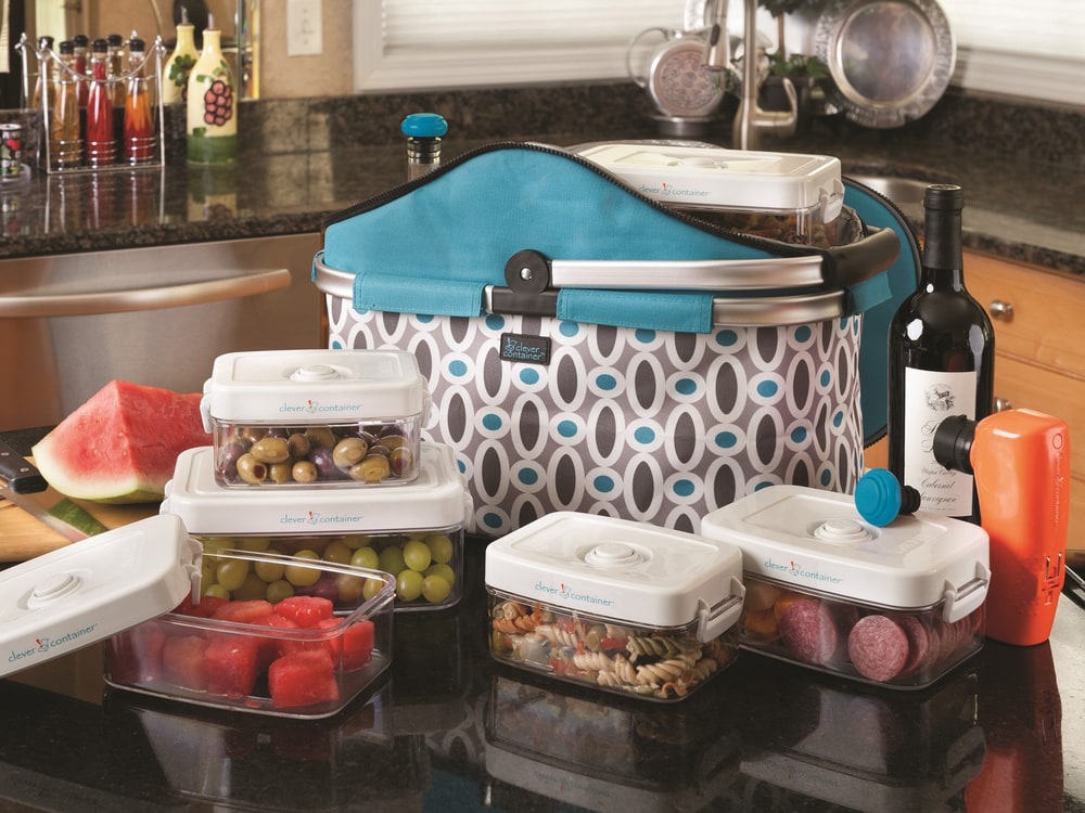 A patterned insulated food carrier and clear Clever Fresh vacuum-seal canisters filled with fruit on a kitchen counter