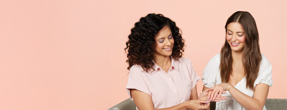 Two women smiling as one shows off a fresh Color Street manicure on the other's hand
