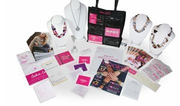 The contents of a 2012 Cookie Lee starter kit: necklaces on display busts, a black Cookie Lee tote bag, catalogs and business supplies