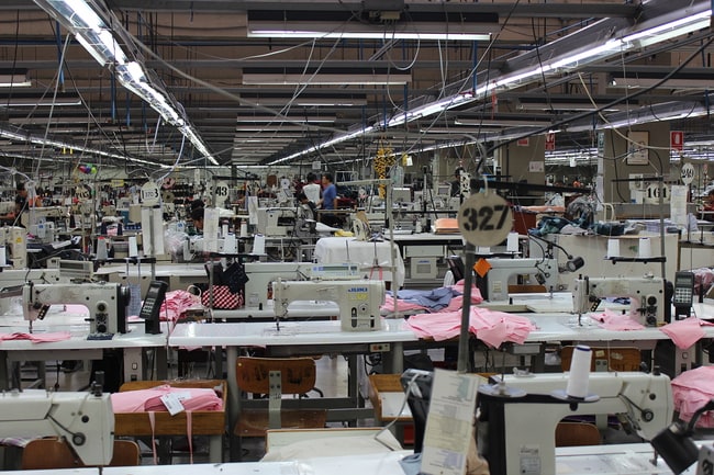 Rows of sewing machines and workers on a large garment factory floor in Peru