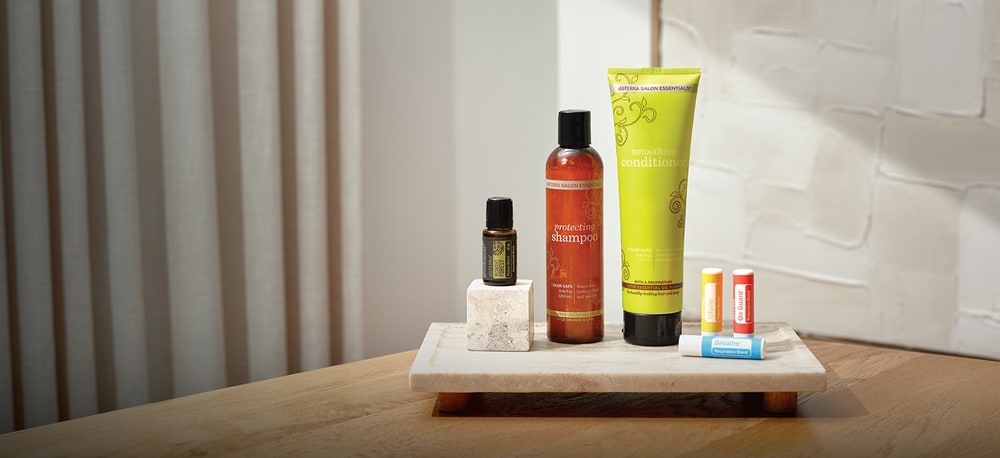 doTERRA Salon Essentials protecting shampoo and smoothing conditioner with a Midnight Forest oil and three lip balms on a marble tray