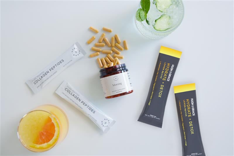 Hugh & Grace Collagen Peptides sticks, Morning supplement capsules and Hydrate + Detox sticks laid out with two drinks