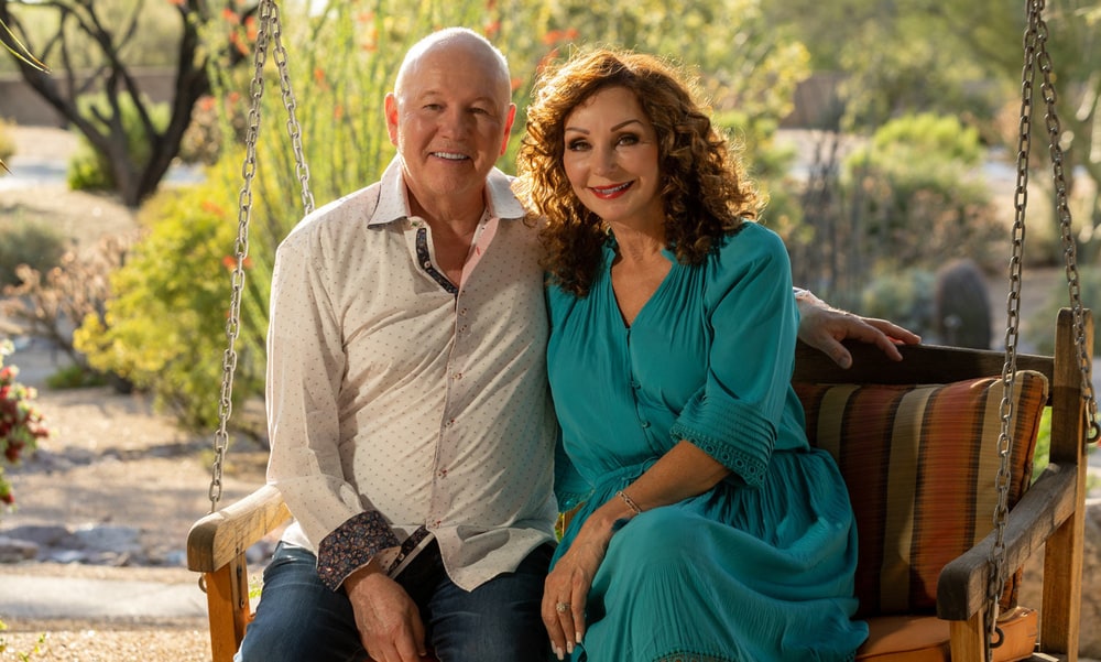 L'BRI founders Brian and Linda Kaminski sitting together on a wooden porch swing in a desert garden