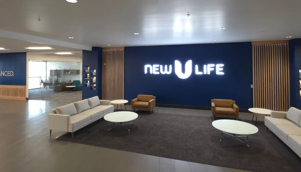 New U Life office lobby in Lehi, Utah, with sofas and a lit company sign on a navy wall