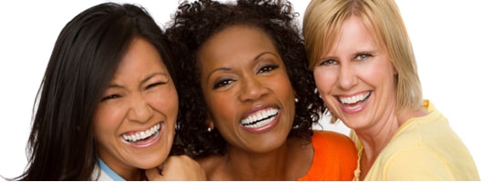 Three smiling women laughing together, cheek to cheek
