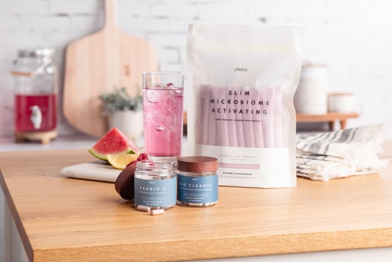 Plexus Slim Microbiome Activating pouch with ProBio 5 and Bio Cleanse jars and a pink drink on a kitchen counter