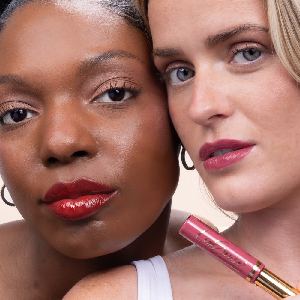 Two women wearing red and berry LipSense lip colors, one holding a pink LipSense tube