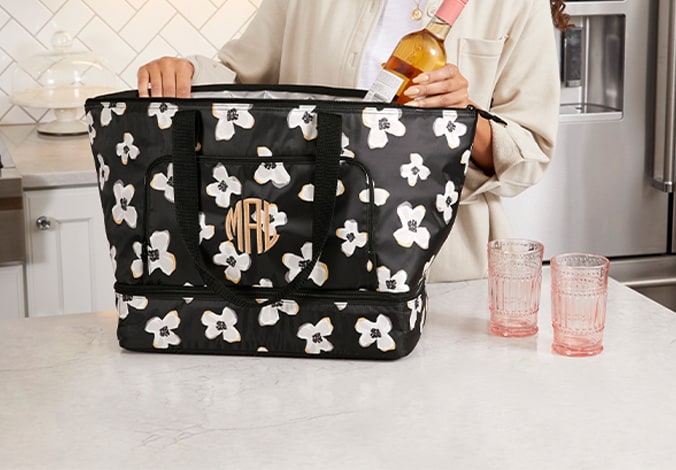 A monogrammed black floral Thirty-One cooler tote being packed on a kitchen counter